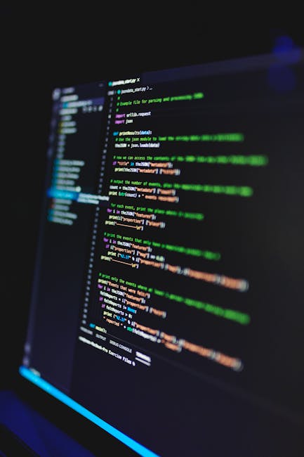 A close-up view of a computer screen displaying lines of colorful programming code in a dark environment. The code is highlighted in shades of green, blue, orange, and white, indicating syntax and fun
